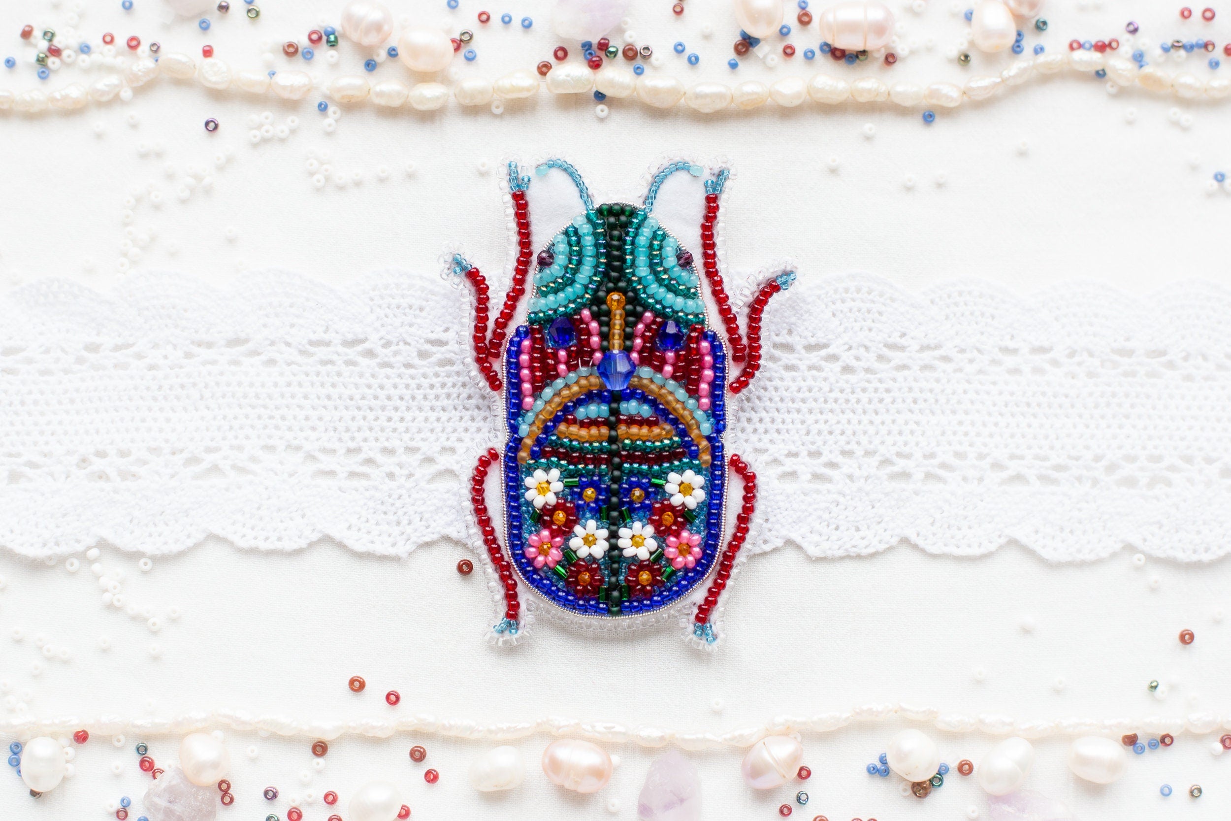 a beaded bug is sitting on a white surface